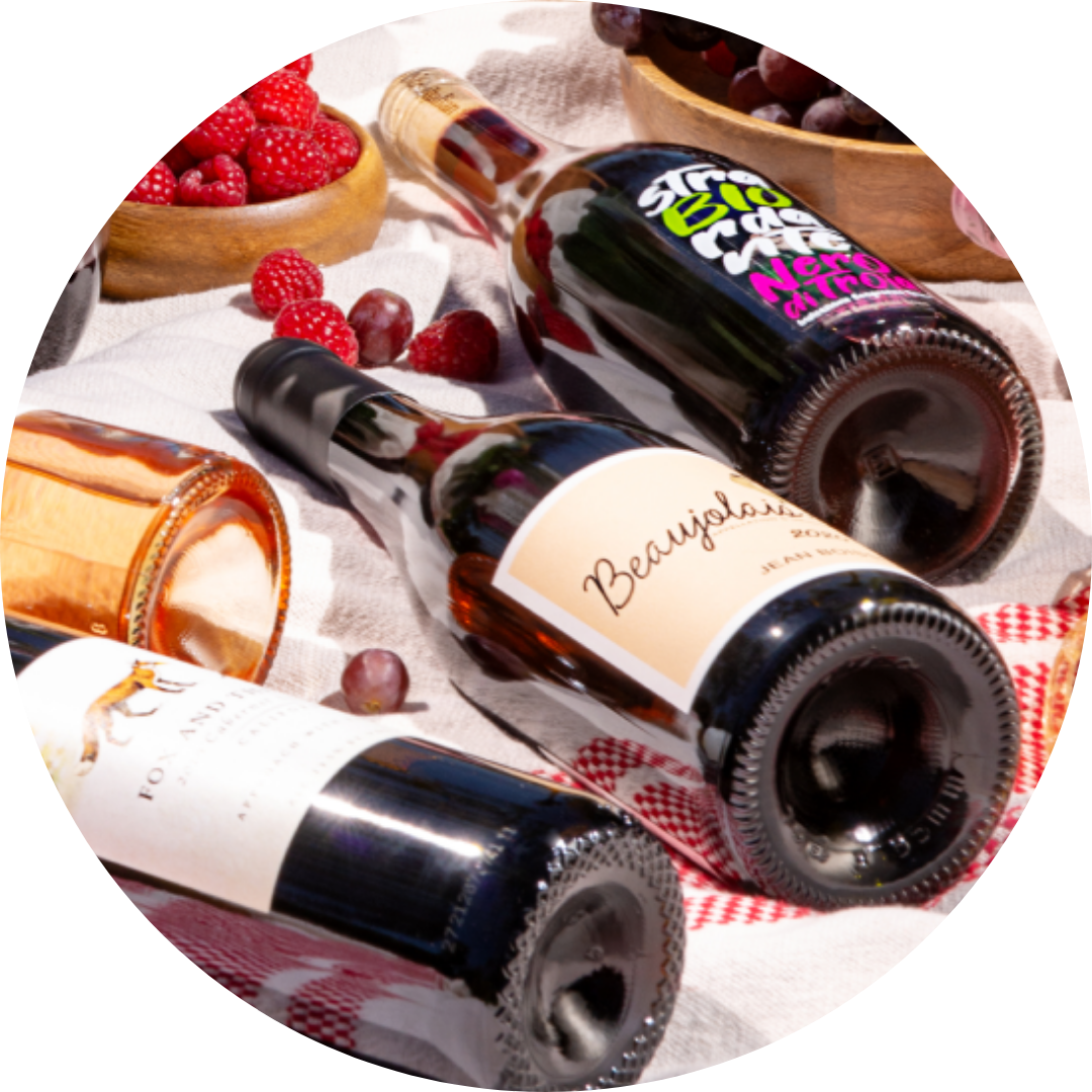 A collection of red wine bottles, some uncorked, lying on a table, representing smooth and approachable red wines.