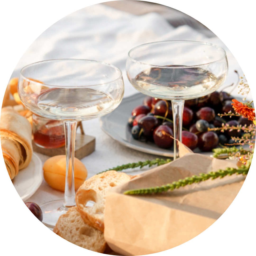 A table set with glasses of white wine, fresh fruit, and appetizers, perfect for a refreshing tasting experience.